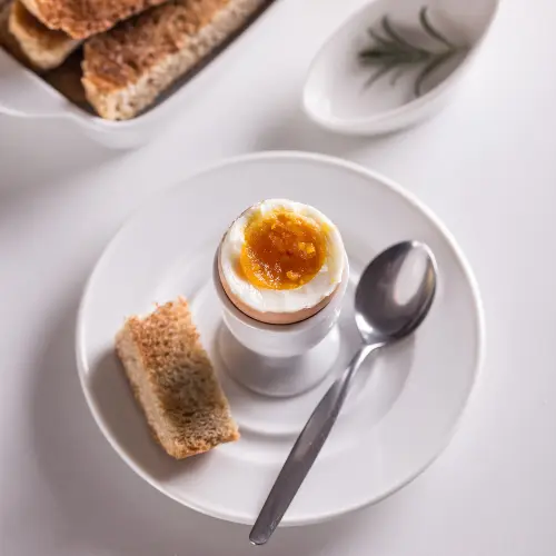 A boiled egg on a plate with toast.